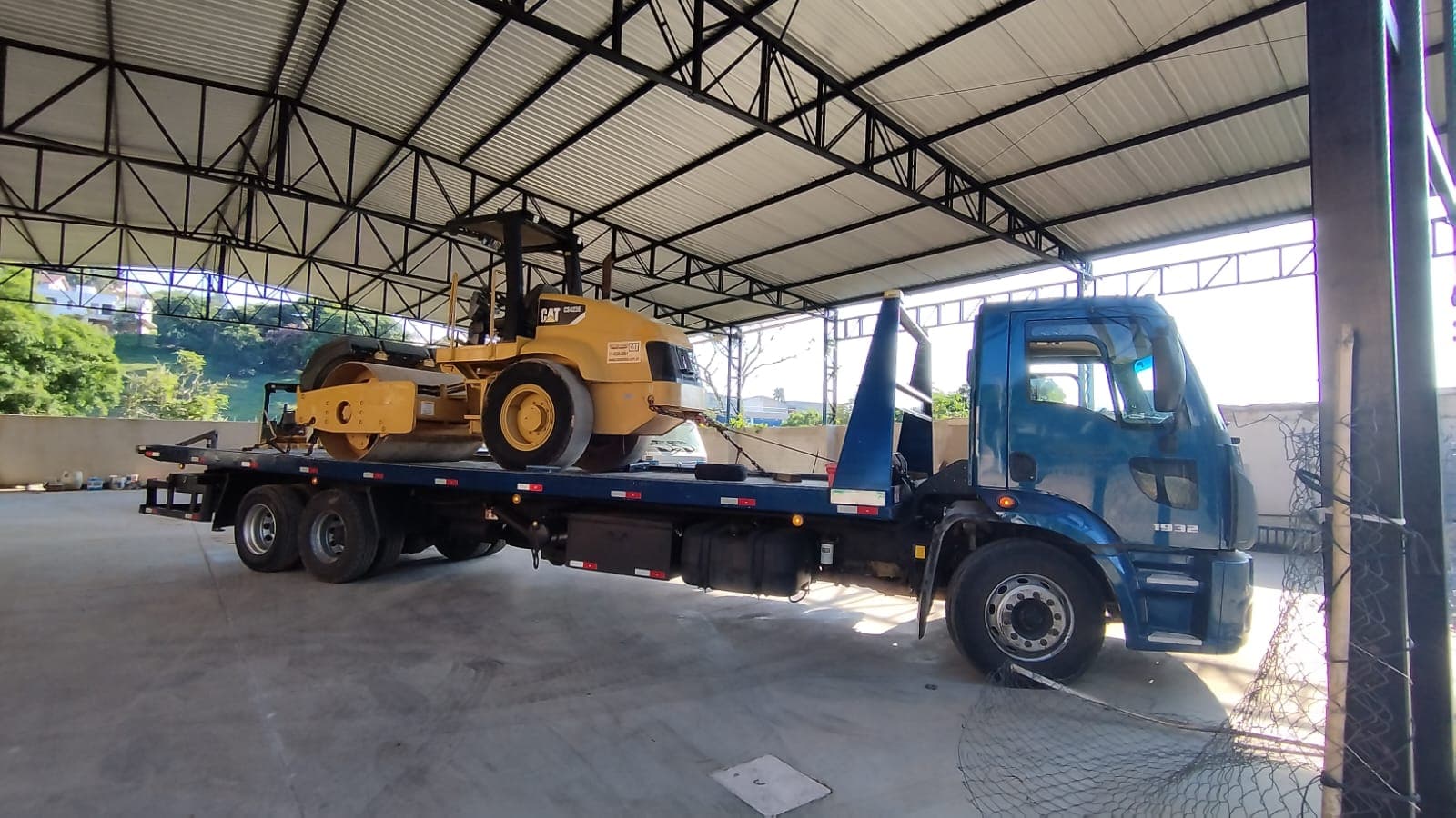 Caminhão da Construloc transportando rolo compactador CAT para locação